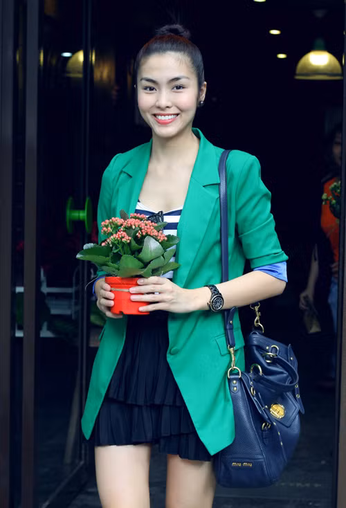 Trẻ trung với váy ngắn xếp li, áo kẻ, blazer xanh và túi đeo vai big size của Miu Miu.