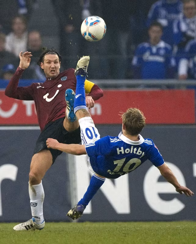 Christian Schulz (áo nâu) của Hannover tranh bóng với Lewis Holtby (Schalke 04) trong trận đấu ở Bundesliga