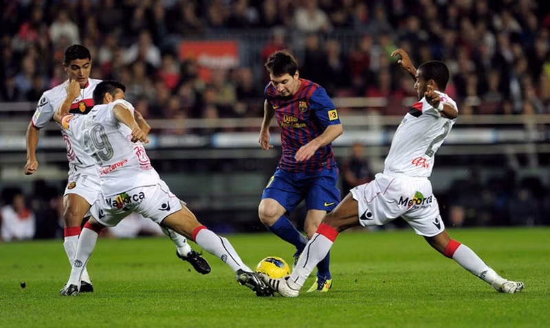 Hai cầu thủ Mallorca cùng lao vào tranh bóng với Lionel Messi trong trận đấu tại La Liga
