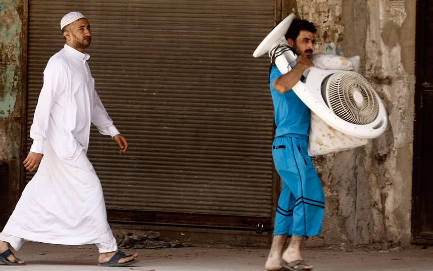 Một người đàn ông đang mang theo chiếc quạt khi chạy trốn khỏi Aleppo.