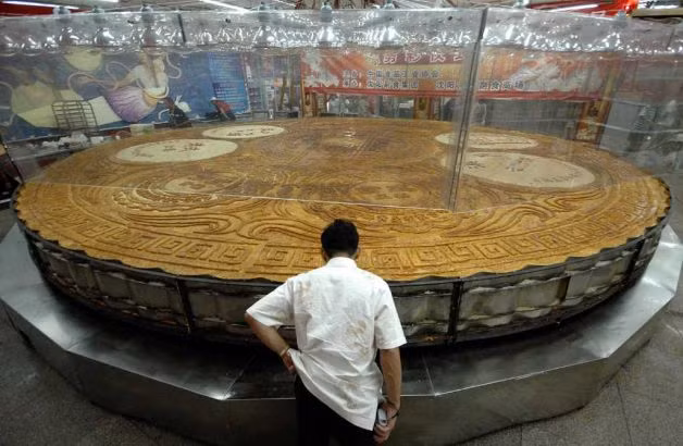 Một đầu bếp kiểm tra chiếc bánh trung thu lớn nhất Trung Quốc mới ra lò tại Thẩm Dương, tỉnh Liêu Ninh vào Tết Trung thu năm 2007. Chiếc bánh này có đường kính 8,15m, độ dày 20 cm, nặng 12,98 tấn và có 10 hương vị. Chiếc bánh đã được làm từ một tấn bột, 12 tấn nhân và nướng trong 10 giờ. Một đầu bếp kiểm tra chiếc bánh trung thu lớn nhất Trung Quốc mới ra lò tại Thẩm Dương, tỉnh Liêu Ninh vào Tết Trung thu năm 2007. Chiếc bánh này có đường kính 8,15m, độ dày 20 cm, nặng 12,98 tấn và có 10 hương vị. Chiếc bánh đã được làm từ một tấn bột, 12 tấn nhân và nướng trong 10 giờ.