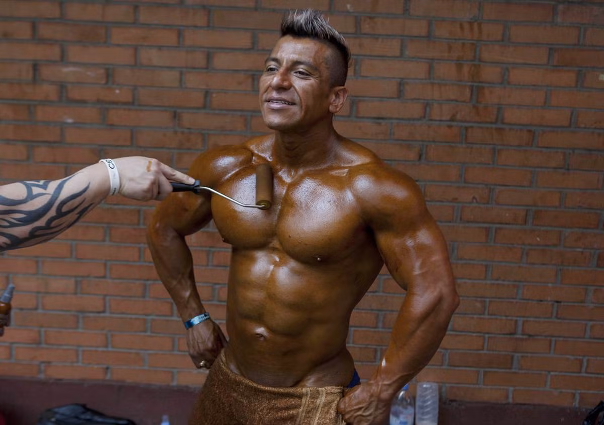 Heriberto Pacheco đang được bôi dầu lên da trước khi thi đấu thể hình ở thủ đô Mexico.