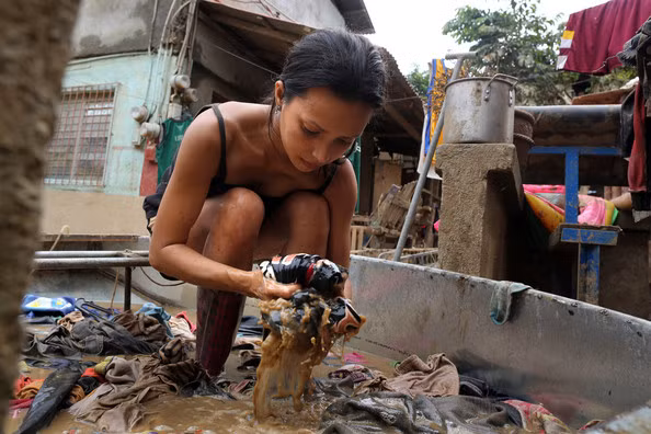 Tìm lại những bộ quần áo bị vùi trong nước lũ.