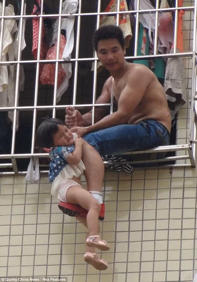 Ông bố dùng chân để đỡ và kéo tay bé gái ở bên ngoài cửa sổ tầng 6. Ông bố dùng chân để đỡ và kéo tay bé gái ở bên ngoài cửa sổ tầng 6.