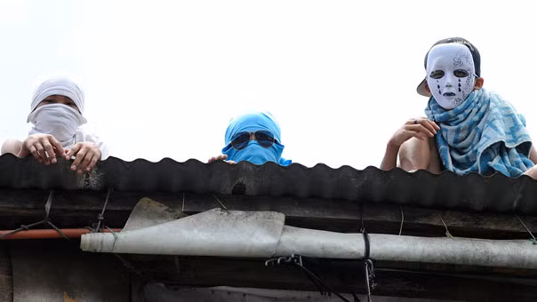 Người dân ở khu ổ chuột che mặt khi các quan chức thành phố đi qua và đang có kế hoạch phá hủy nhà của họ để làm đường cho một dự án phát triển đô thị trong khu tài chính Manila.