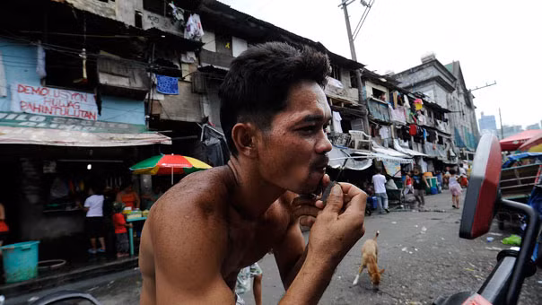 Một người đàn ông đang cạo râu trong khu ổ chuột ở Manila.