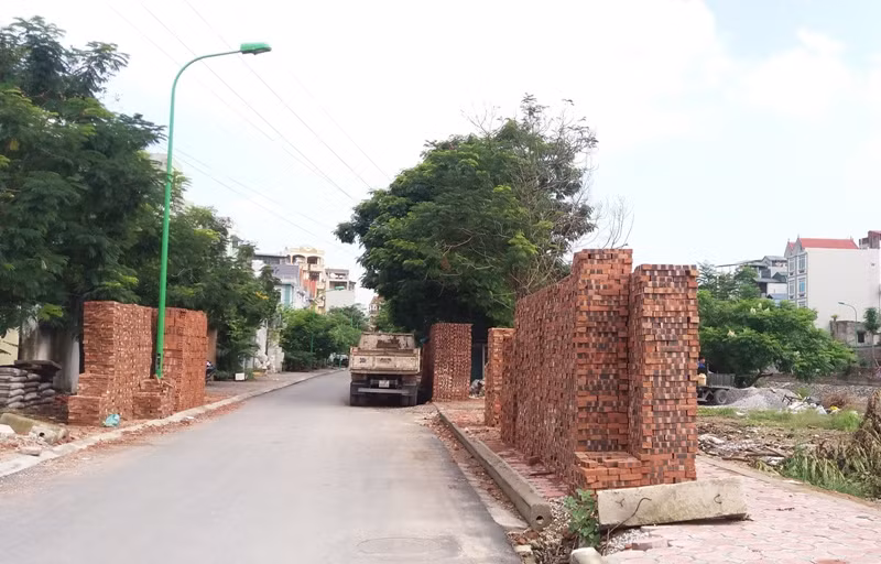 Không chỉ tập kết ngay trên vỉa hè mà ông Lê Hồng Quang, chủ cửa hàng vật liệu xây dựng còn chiếm luôn một phần của khu vui chơi để để làm nơi kinh doanh cát, đá. Ảnh Trần Việt.