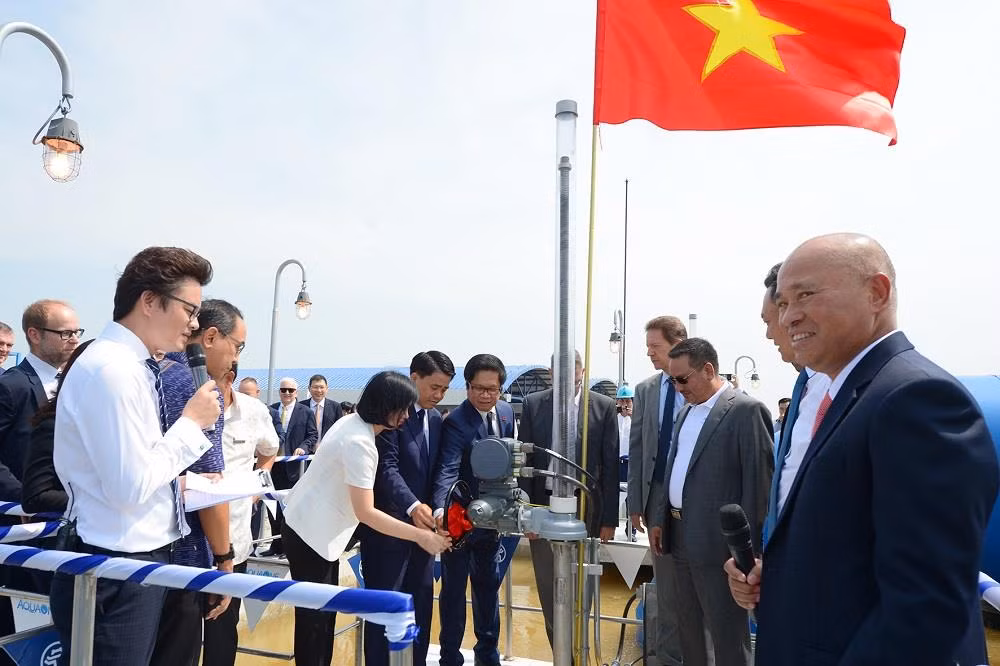 Lãnh đạo Thành phố Hà Nội, lãnh đạo phòng Thương mại và Công nghiệp Việt Nam cùng các đại sứ, khách mời uống thử nước ngay tại vòi trong nhà máy. ảnh: QT.
