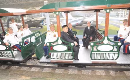 Chủ tịch Kim Jong Un cùng tướng lĩnh thăm qua khu trưng bày ngoài trời trên tàu điện. Đằng sau là những chiếc vận tải An-2, tiêm kích F-6 của Không quân Triều Tiên.