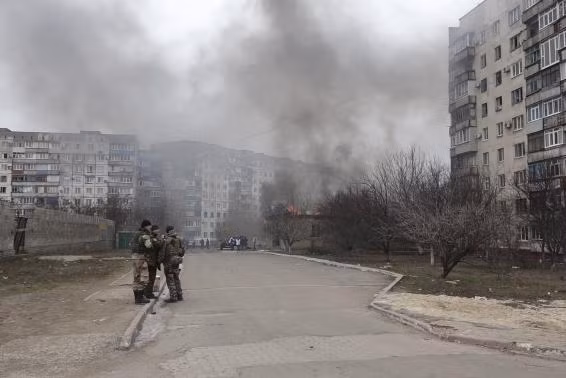 Lực lượng an ninh Ukraine đứng trước tòa nhà cháy sau vụ tấn công của lực lượng ly khai tại Mariupol. Lực lượng an ninh Ukraine đứng trước tòa nhà cháy sau vụ tấn công của lực lượng ly khai tại Mariupol.