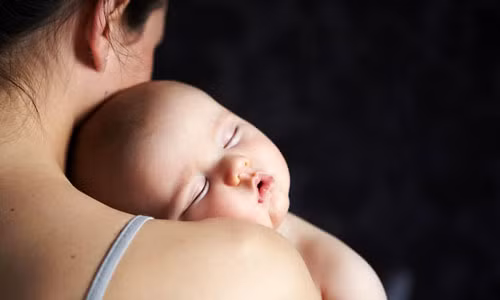Thay vì để bé ngủ say trong vòng tay bạn rồi mới đưa vào cũi, hãy cho bé vào giường khi còn đang mơ màng. Ảnh: Inmagine.