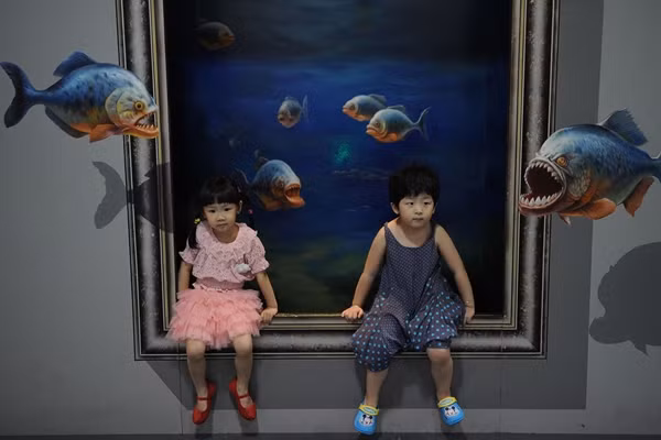 Hai em bé ngồi trong bể cá . Hai em bé ngồi trong bể cá .