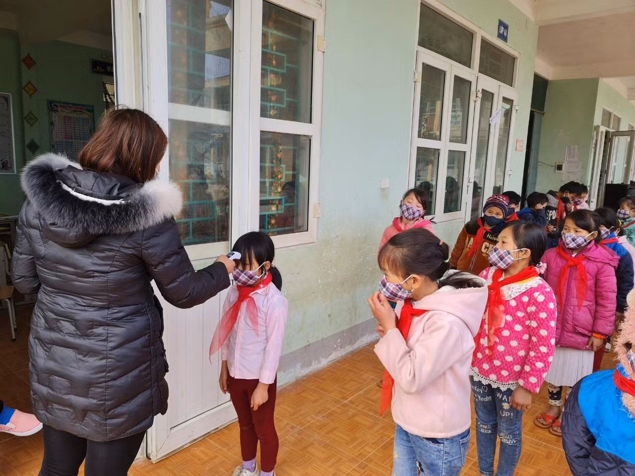 Đo nhiệt độ cho học sinh tại trường Phổ thông bán trú Tiểu học Đồng Văn B. Nhiều em học sinh còn bỡ ngỡ nhưng thực hiện tốt việc đo nhiệt độ trước khi vào lớp.
