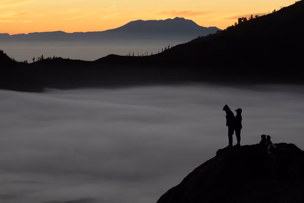 Dân làng đứng trên một miệng núi lửa ở dãy núi Bromo trong lúc trời mặt trời lên vào lễ hội Kasada truyền thống ở tỉnh Đông Java, Indonesia, 04/08/2012. Dân làng thường ném vật nuôi và các loại nông sản vào trong miệng núi lửa trên dãy Bromo để cảm ơn đến thần Hindu vì đã ban cho họ sự an toàn và thịnh vượng.