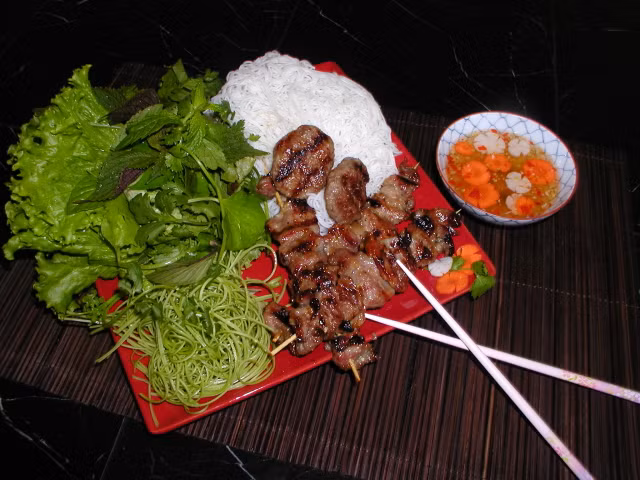 4. Bún chả Hà Nội Bước vào quán bún chả Hà Nội là bạn đã cảm thấy thèm ăn khi ngửi mùi thơm của những miếng thịt đang cháy xèo xèo trên bếp than đỏ rực. Chén bún chả khi dọn lên có sự pha quyện nhiều màu sắc: màu nâu của miếng chả đã nướng hơi cháy sém, màu đỏ của cà rốt, ớt và kết hợp với màu xanh tươi của rau xanh. Vị ngọt và mềm của từng miếng thịt, vị chua chua của nước mắm, chút “sần sật” của miếng cà rốt hoặc đu đủ, vị thơm của các loại rau khiến cho món ăn này thật hoàn hảo. Ở Hà Nội có nhiều hàng bún chả nổi tiếng như Hàng Mành, nhà hàng bún chả Hà Thành (5 N7A Nguyễn Thị Thập, Cầu Giấy)...