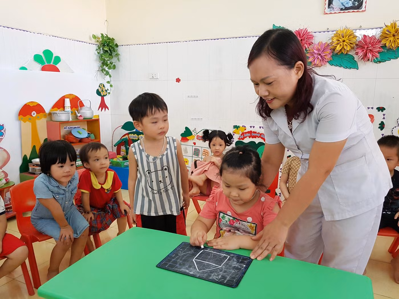 Cô giáo Phạm Thị Thanh dạy trẻ lớp 4 tuổi tập vẽ (Ảnh: Lã Tiến)