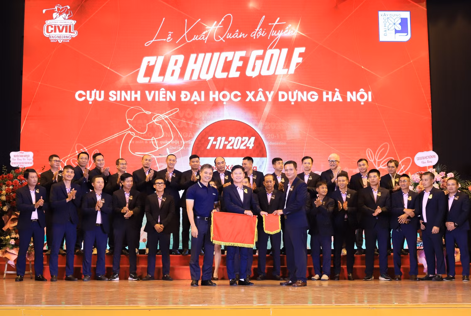 Hiệu trưởng Trường Đại học Xây dựng Hà Nội thực hiện nghi thức trao cờ xuất quân và băng đeo cho đại diện Đội tuyển Câu lạc bộ HUCE golf Cựu sinh viên Trường Đại học Xây dựng Hà Nội. Ảnh: HUCE.