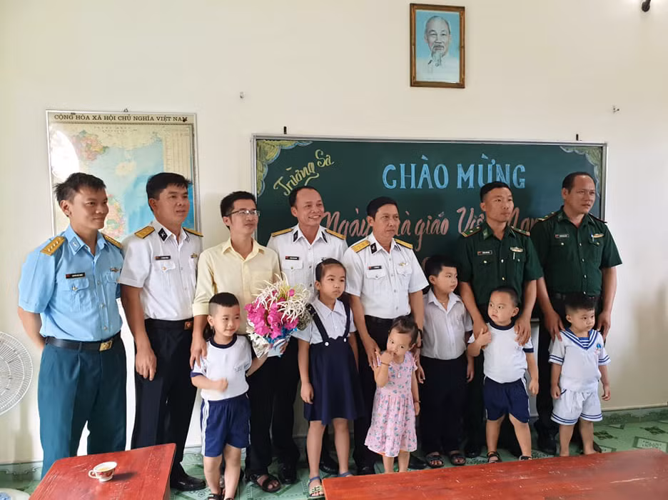 Phụ huynh, các chiến sĩ, người dân cùng thầy giáo và các em học sinh chụp hình lưu niệm. (Ảnh: H.T)