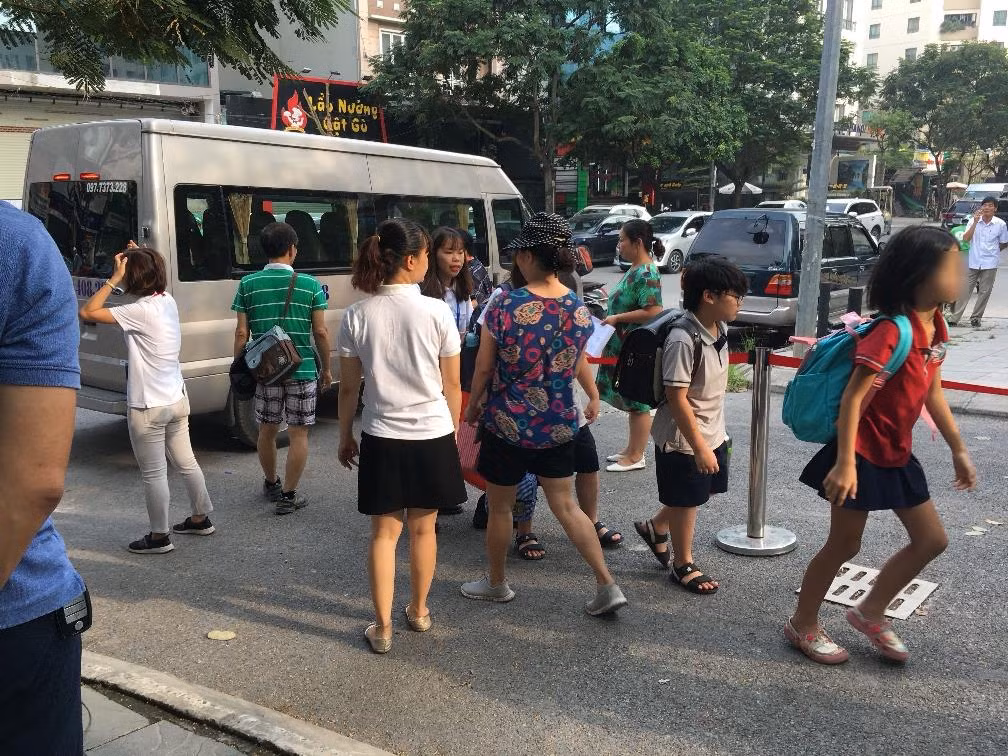 Học sinh xuống xe được yêu cầu xếp hàng kiểm đếm trước khi vào trường.