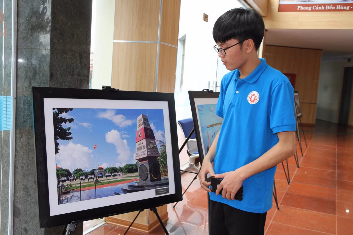 Nam sinh viên Đại học Hùng Vương xúc động trước hình ảnh Chào cờ đầu tuần của tác giả Trọng Thiết trên đảo Trường Sa. Ảnh: Vũ Phương.