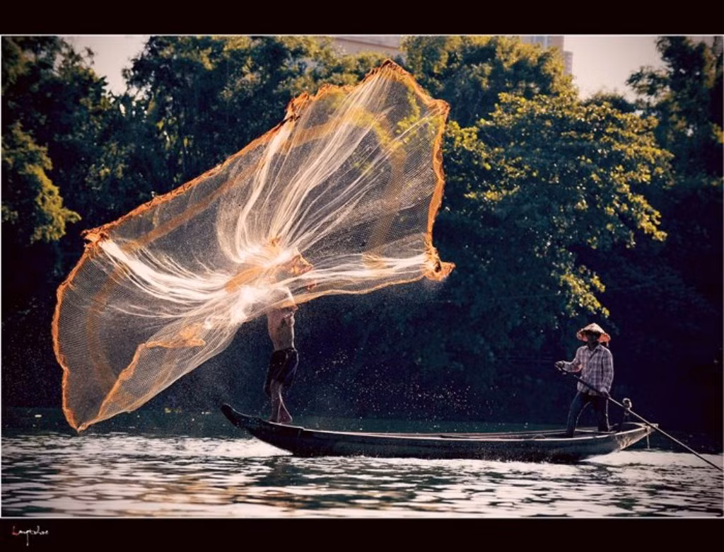 Bác chài đang cố vươn đôi tay để tung lưới thật xa...không ai nghĩ rằng đây là một tấm lưới mà nghĩ nó giống một tấm váy hoa xòe đang bay trong gió