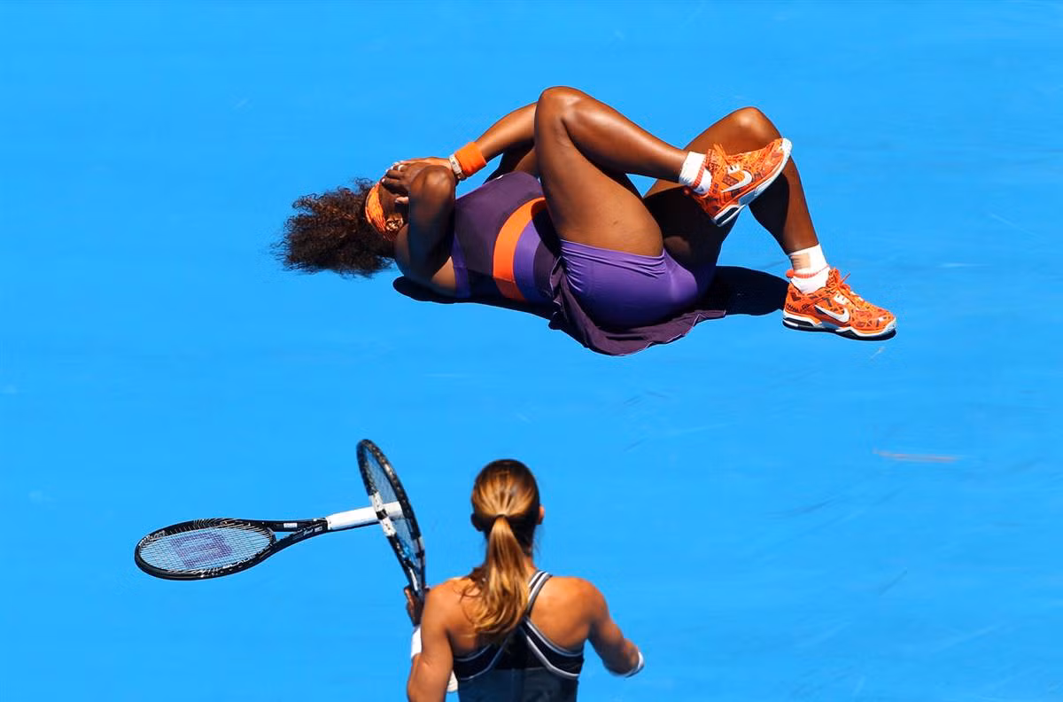 Edina Gallovits-Hall của Romania nhìn Serena Williams nằm lăn trên sân trong trận đấu tại vòng đầu tiên của giải Australia mở rộng năm 2013 ở Melbourne vào ngày 15/1. Williams đã giành chiến thắng sau hai séc đấu với tỷ số 6-0, 6-0.