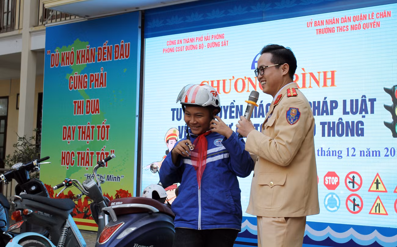Các em học sinh Trường Trung học cơ sở Ngô Quyền được hướng dẫn cách đội mũ bảo hiểm đúng cách (Ảnh: Lã Tiến)