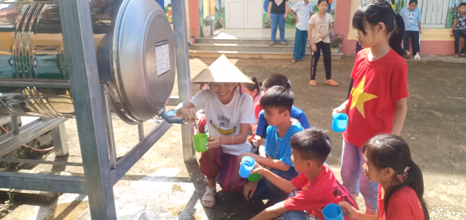Học sinh sử dụng nước từ hệ thống lọc nước.
