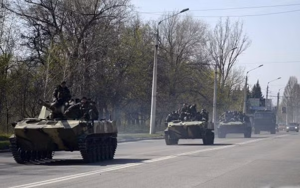 Ảnh: Đội quân mặt nạ có vũ trang lái xe bọc thép mang cờ Nga di chuyển bên ngoài thị trấn Kramatorsk hôm 16/4. Ảnh: Đội quân mặt nạ có vũ trang lái xe bọc thép mang cờ Nga di chuyển bên ngoài thị trấn Kramatorsk hôm 16/4.