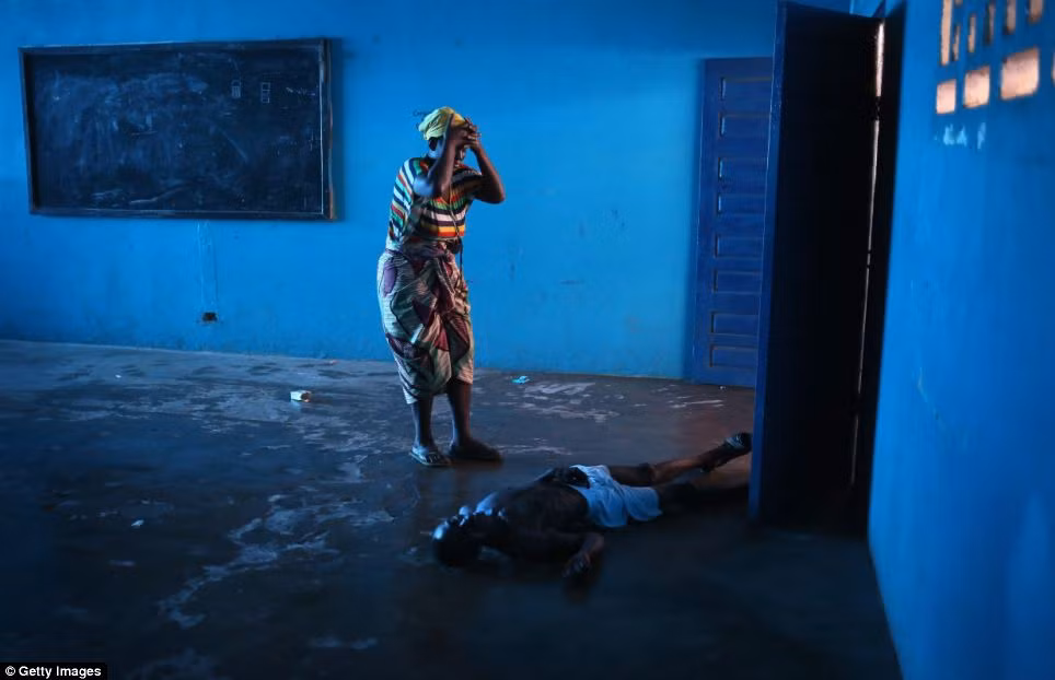 Người phụ nữ ôm đầu khóc khi thấy chồng nghi nhiễm Ebola nằm bất tỉnh trên đất. Người phụ nữ ôm đầu khóc khi thấy chồng nghi nhiễm Ebola nằm bất tỉnh trên đất.