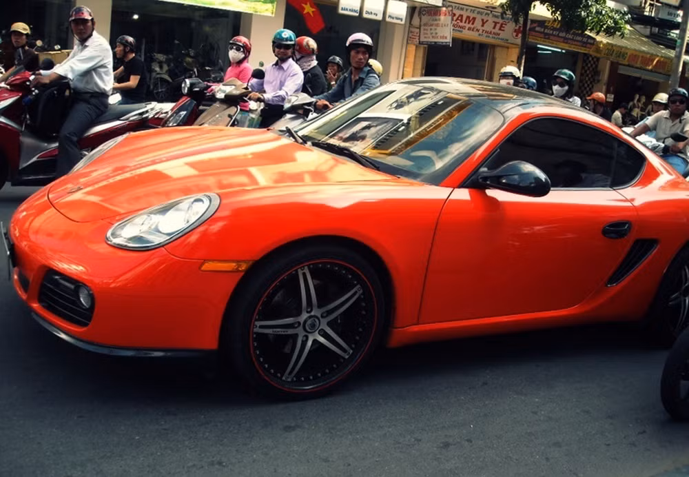 Chiếc Porsche màu cam nổi bật giữa phố thu hút mọi ánh nhìn.