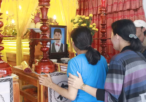 Chị Huỳnh Thị Thanh Thảo (mặc áo xanh), vợ anh Lộc và mẹ bé Tài, khóc nức nở bên ảnh và quan tài chồng, con.