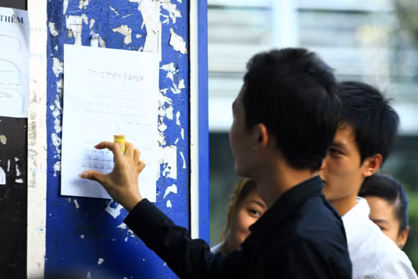 Hồn nhiên dán tờ rơi lên bốt điện thoại thẻ