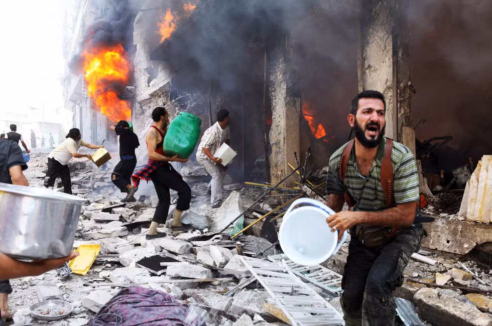 Những người dân Syria dập lửa tòa nhà trúng đạn của quân chính phủ hôm 4/9 làm 4 người tử vong