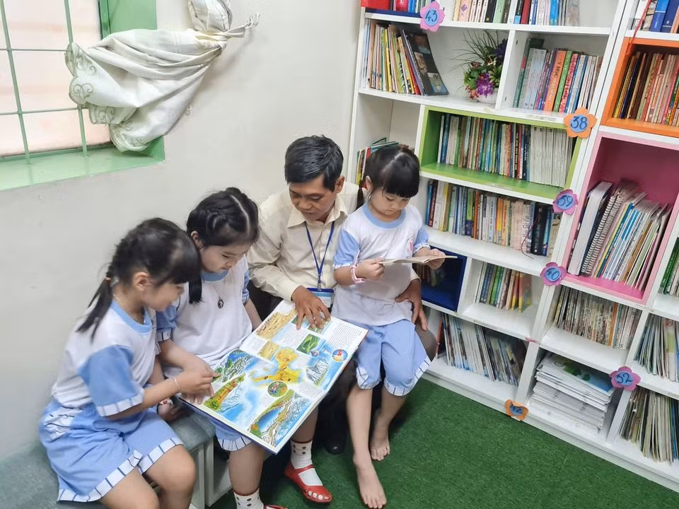 Học sinh trong vòng tay trìu mến của thầy Nguyễn Văn Hùng ở phòng đọc sách (ảnh: P.L)
