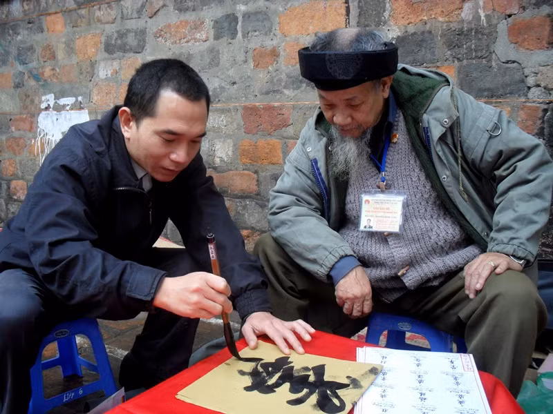 Khách xem chữ thử cầm bút lông.