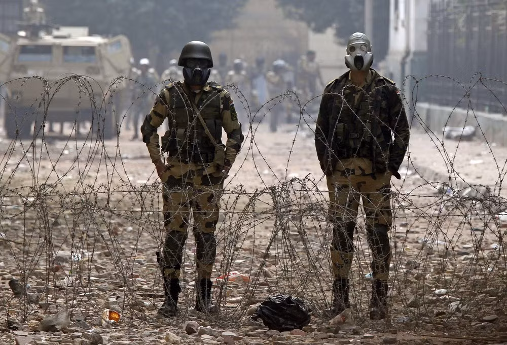 Binh sỹ Ai Cập đứng gác sau hàng rào dây thép gai ở quảng trường Tahrir, thủ đô Cairo đề phòng người biểu tình quá khích (ảnh chụp ngày 22/11/2011) Binh sỹ Ai Cập đứng gác sau hàng rào dây thép gai ở quảng trường Tahrir, thủ đô Cairo đề phòng người biểu tình quá khích (ảnh chụp ngày 22/11/2011)