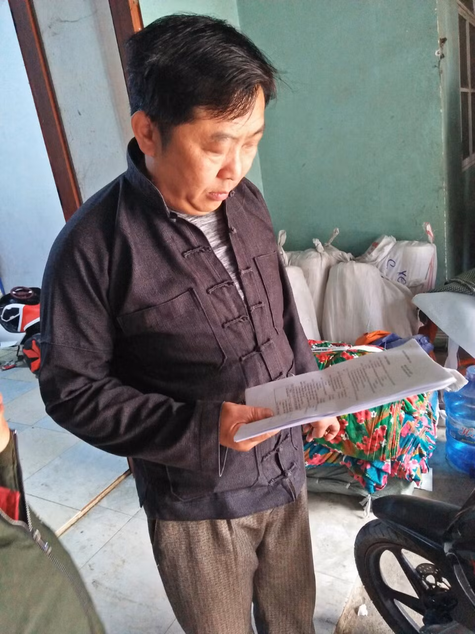 Một phụ huynh ở Phố Cáo cầm bài ôn của các con em. Một phụ huynh ở Phố Cáo cầm bài ôn của các con em.