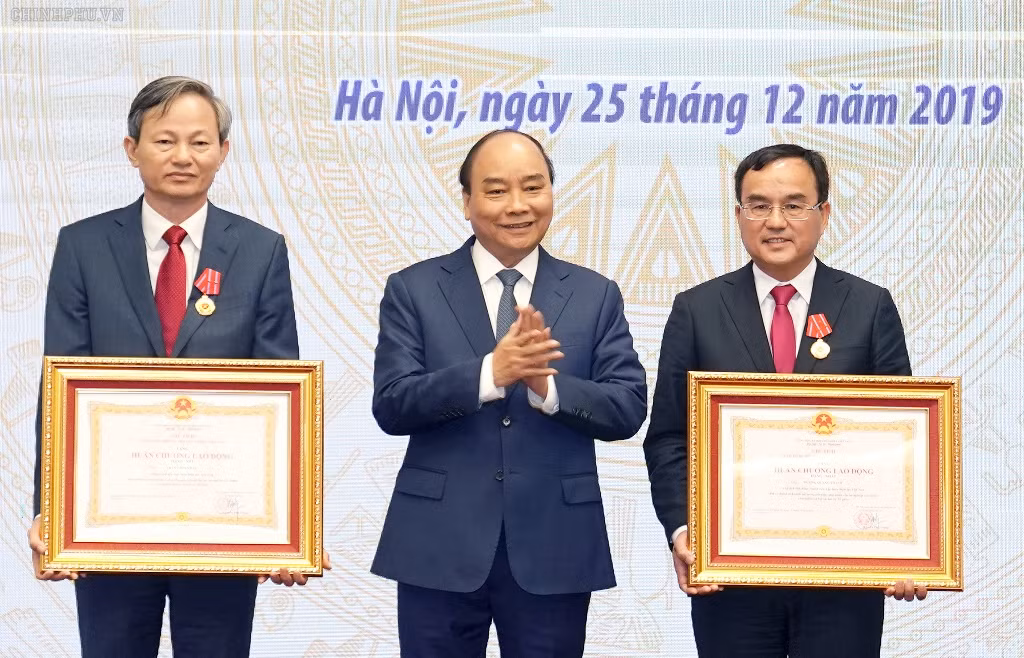 Thủ tướng Nguyễn Xuân Phúc trao Huân chương Lao động hạng Nhất tặng Chủ tịch Hội đồng thành viên EVN Dương Quang Thành, Huân chương Lao động hạng Nhì tặng Tổng Giám đốc EVN Trần Đình Nhân. Ảnh: VGP