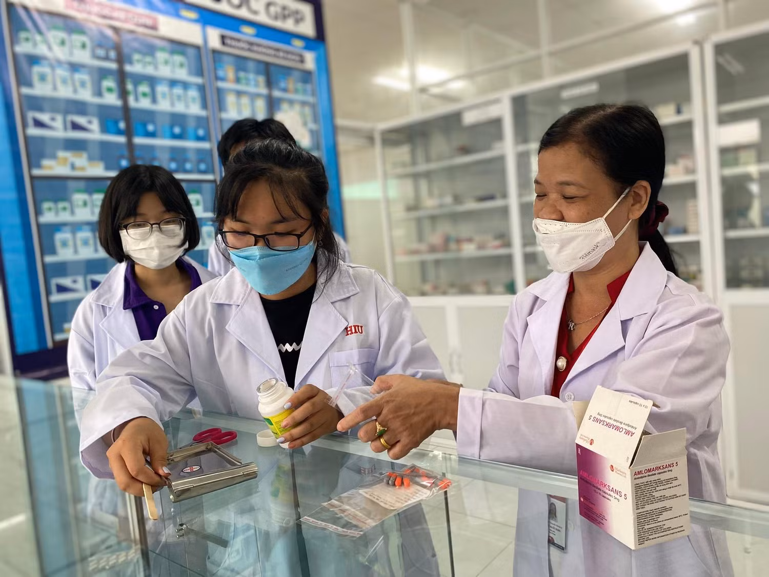 Dược sĩ Định (bìa phải) đang hướng dẫn học sinh thao tác với thuốc thật trong chương trình (ảnh: HIU) Dược sĩ Định (bìa phải) đang hướng dẫn học sinh thao tác với thuốc thật trong chương trình (ảnh: HIU)