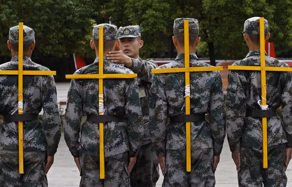 Tân binh Trung Quốc huấn luyện điều lệnh đội ngũ phải đeo giá chữ thập giữ cho lưng thẳng. Tân binh Trung Quốc huấn luyện điều lệnh đội ngũ phải đeo giá chữ thập giữ cho lưng thẳng.