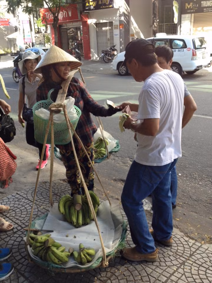 Khách du lịch Trung Quốc dùng Nhân dân tệ thanh toán khi mua chuối của người bán hàng rong trên vỉa hè Đà Nẵng. Người bán chuối không chấp nhận việc thanh toán bằng Nhân dân tệ và yêu cầu thanh toán bằng tiền Việt Nam. Ảnh: Nguyễn Duy Khoái
