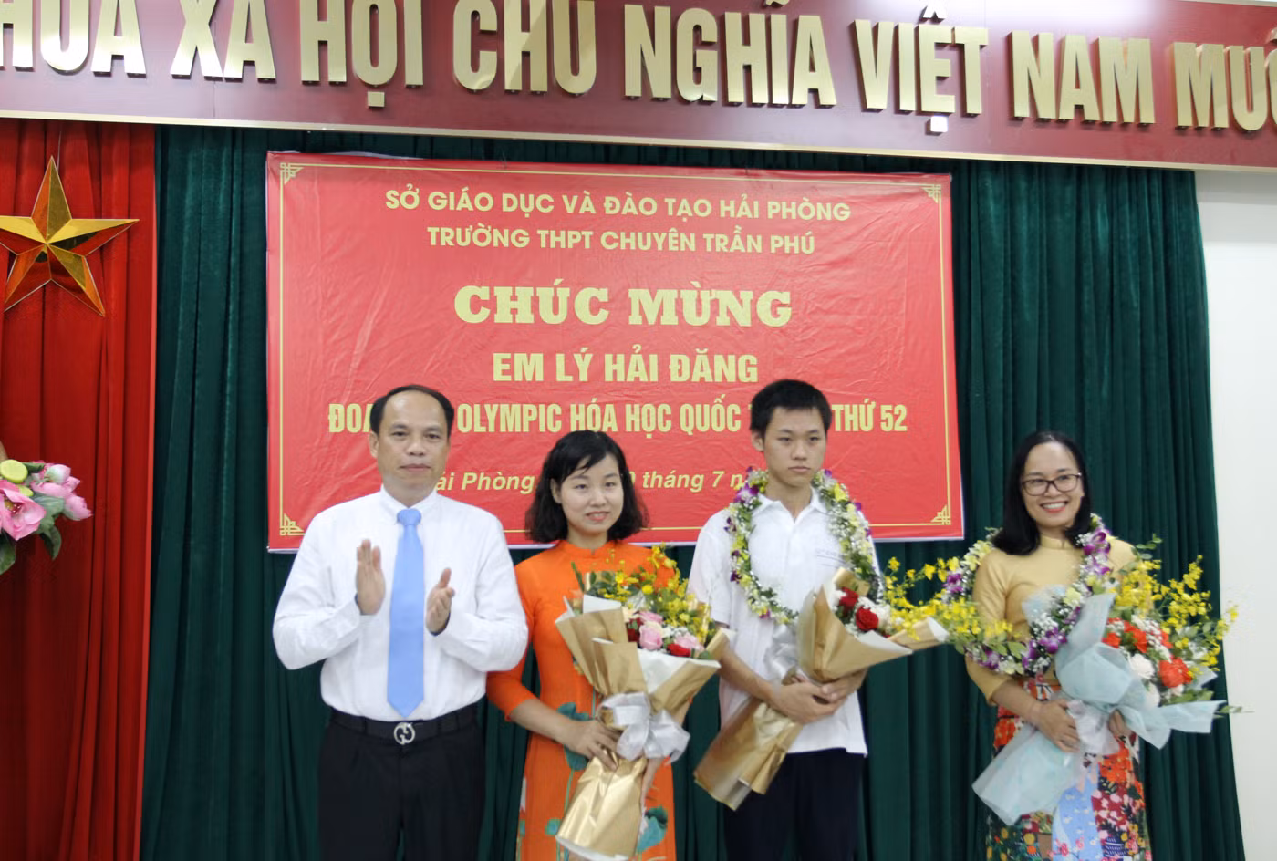 Phó giáo sư, Tiến sĩ Lê Quốc Tiến, Giám đốc Sở Giáo dục và Đào tạo Hải Phòng tặng hoa chúc mừng em Lý Hải Đăng cùng cô giáo chủ nhiệm Nguyễn Thị Thanh Thúy (Ảnh: Lã Tiến)
