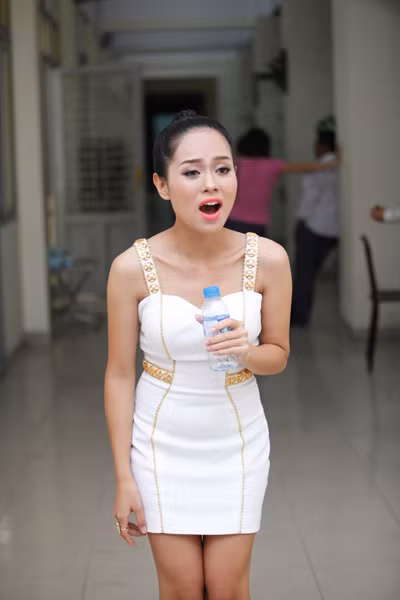 Cô cầm chai nước suối làm micro để tập phong cách biểu diễn trong hậu trường.
