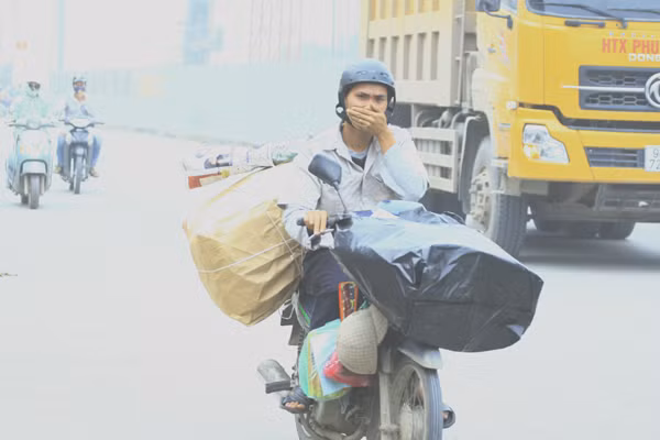 Một người tham gia giao thông đi trên đoạn Mai Dịch - Linh Đàm không đeo khẩu trang phải bịt mũi vì khói bụi kinh hoàng