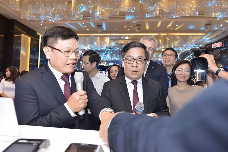 Hình ảnh đại biểu tham quan và khách hàng điền vào form chuyển đổi từ thẻ từ sang thẻ chíp tại Gian trưng bày của Vietcombank:.