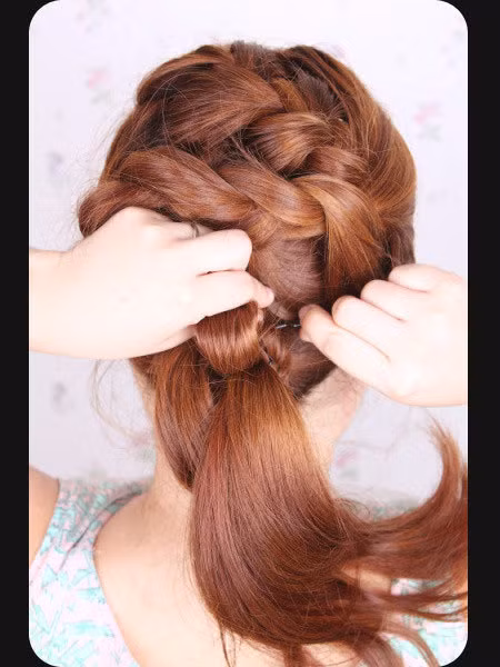 Sau đó chia phần tóc được tết gọn lại thành nhiều phần rồi lần lượt cuốn lên cuộn vào chân tóc.