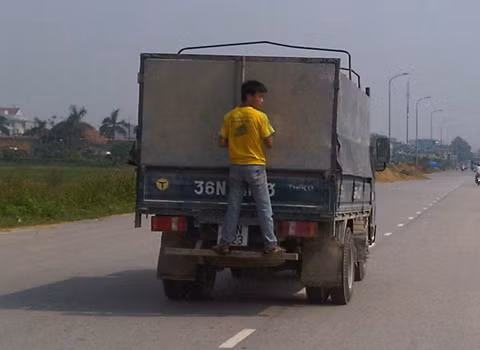 Chàng trai bám sau đuôi xe tải (Ảnh: Như Trưng).