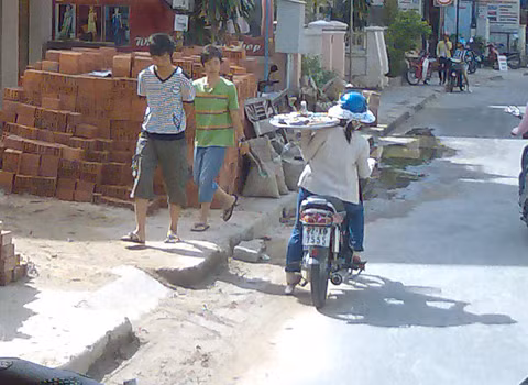 Đi xe máy, một tay bê mâm mỳ Quảng, chụp tại Hội An. Ảnh: Trần Huyền