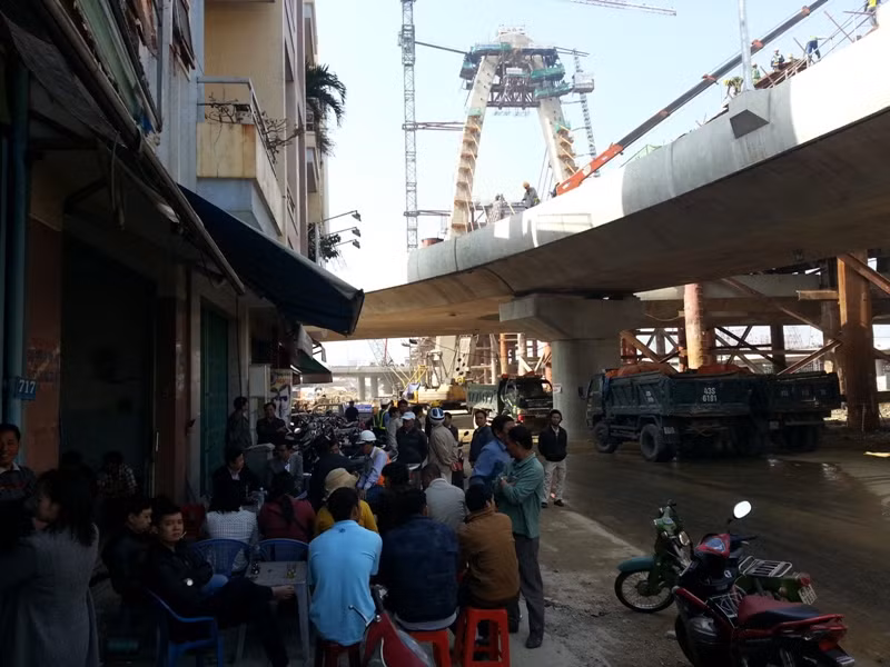 Hàng chục hộ dân có nhà bị ảnh hưởng bởi công trình cầu vượt ngã ba Huế tụ tập dưới chân cầu đang xây dang dở để kiến nghị. Ảnh Thùy Linh